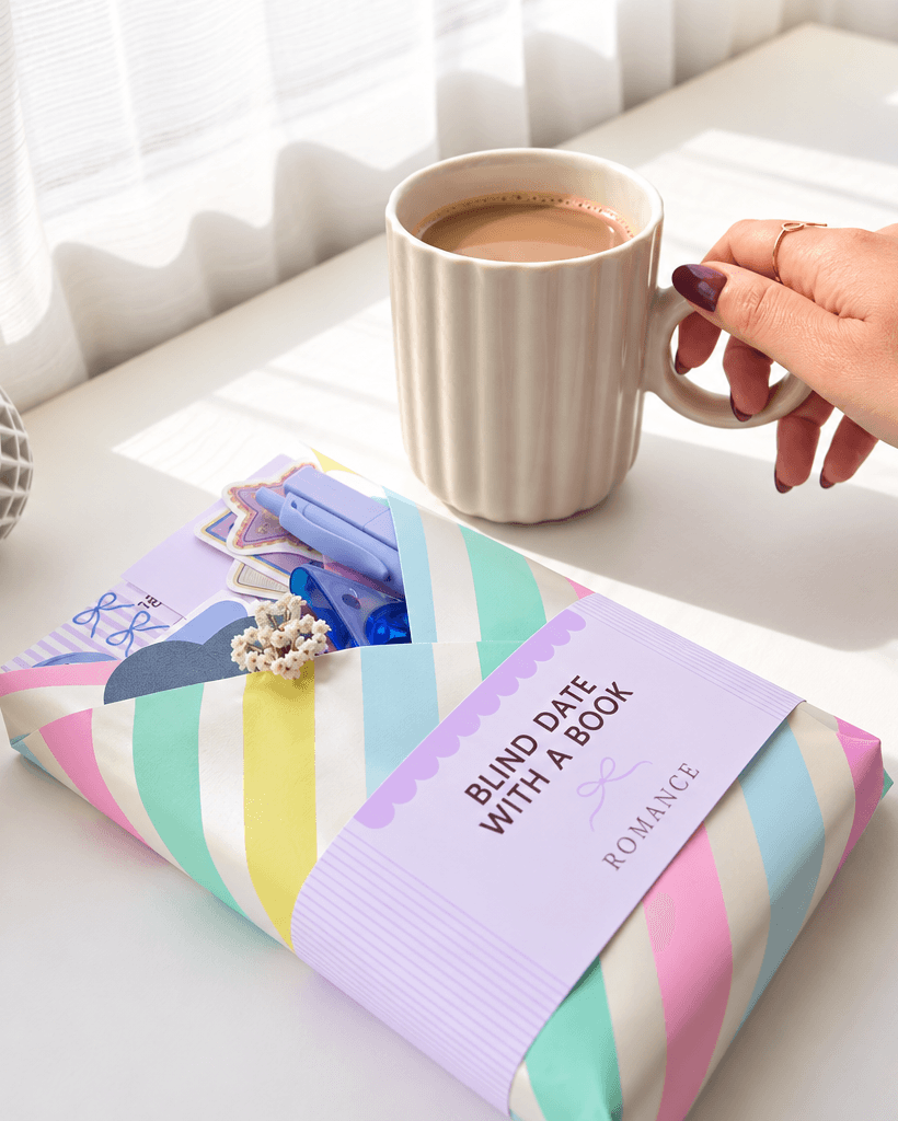 A colorful blind-date-with-a-book parcel beside coffee in sunlight